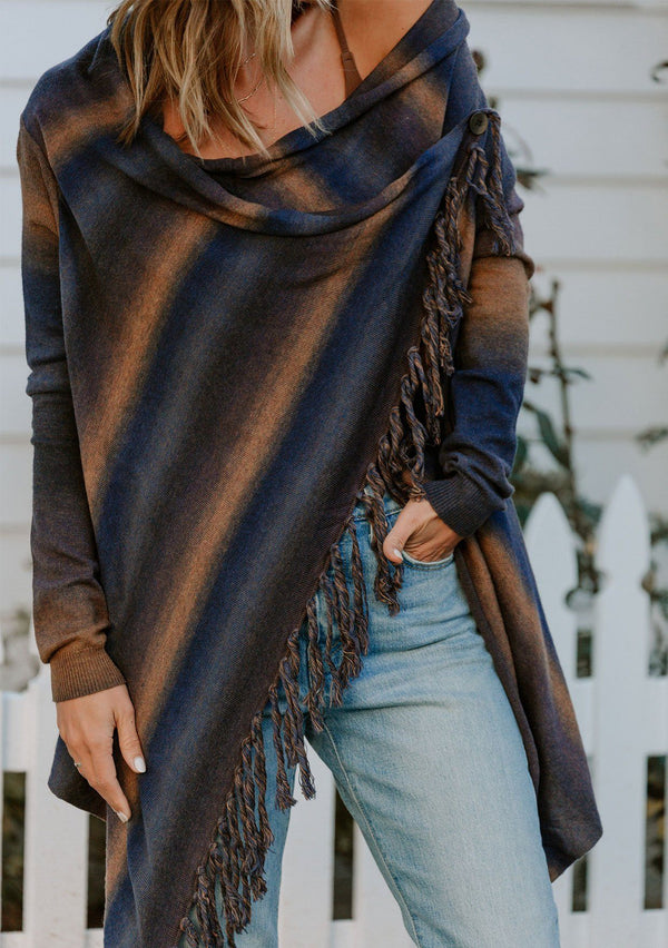 [Color: Midnight/Mustard] A model wearing a navy blue and mustard yellow space dye stripe sweater. With a side button closure, long sleeves, and a fringed waterfall hemline. 