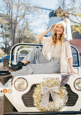 [Color: Sand/Grey] A blond woman wearing a lightweight hooded poncho. Featuring a fringed asymmetric hemline, an oversize hood, and a multi color striped pattern.