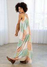 [Color: Natural/Mint] A model wearing a sleeveless patchwork paisley maxi dress. With a deep v neckline in front and back, adjustable spaghetti straps, and side pockets.