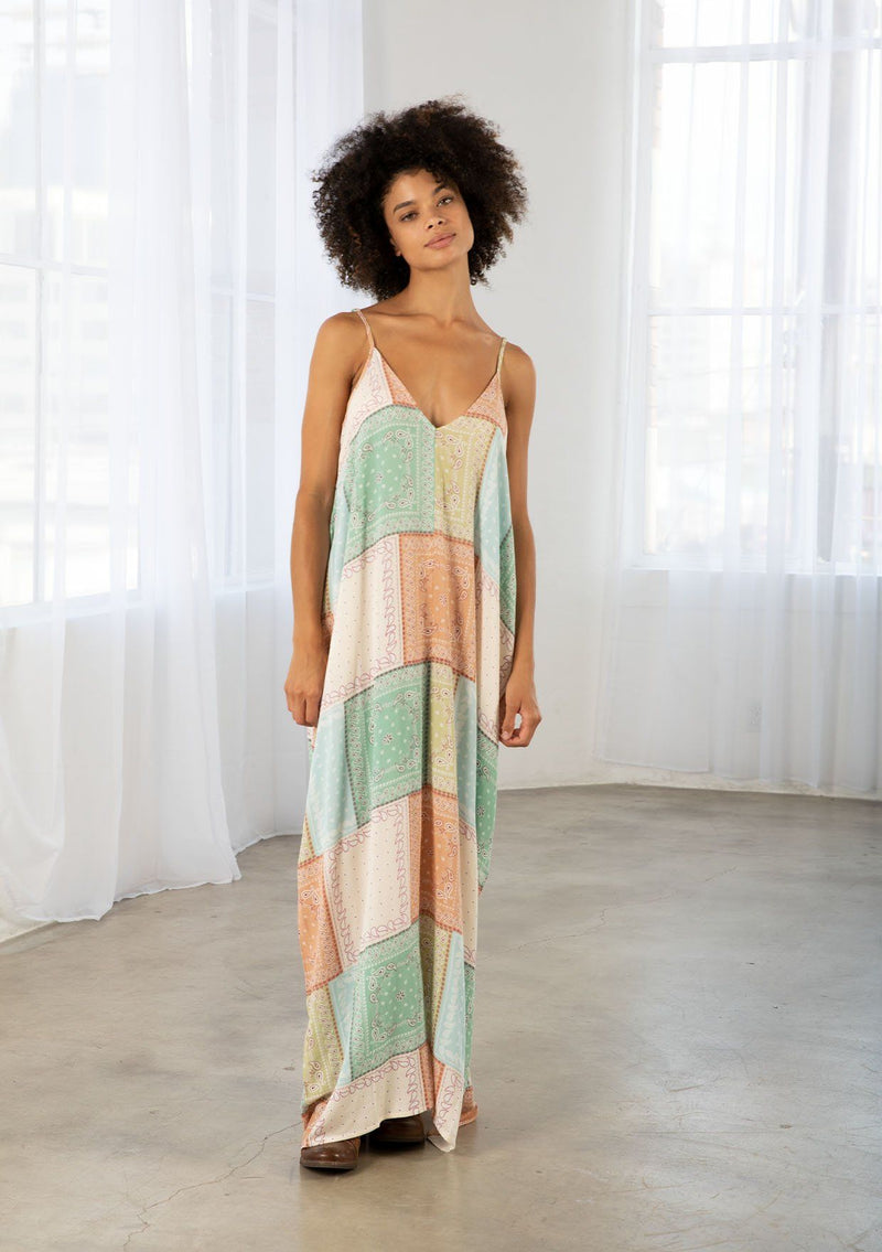 [Color: Natural/Mint] A model wearing a sleeveless patchwork paisley maxi dress. With a deep v neckline in front and back, adjustable spaghetti straps, and side pockets.