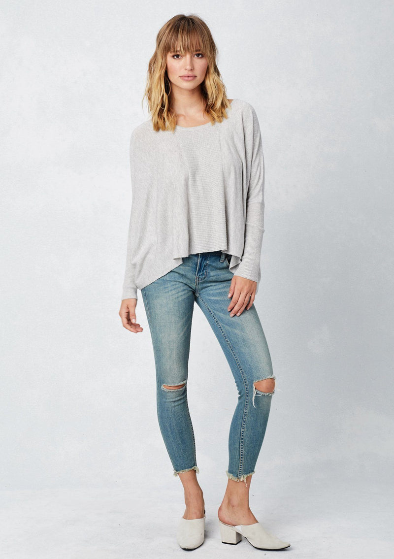 [Color: Light Heather Grey] A blonde model wearing a grey cozy throw on pullover with comfortable batwing sleeves. This relaxed fit sweater features a scoop neckline, flowy hem, and rib details at the sleeve and center front. 