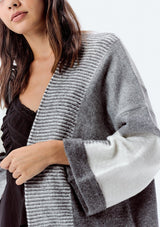 [Color: Heather Grey/Ivory] A detail image of a brunette model wearing an ultra cozy color block cardigan in grey. Featuring wide long sleeves, dropped shoulders, an open front, and rib accents throughout. Perfect for Fall layering. 