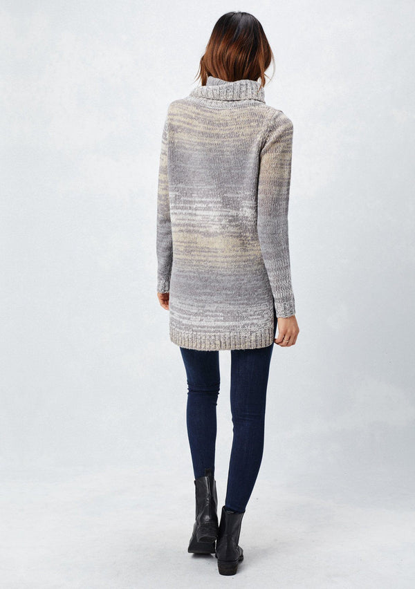 [Color: Grey/Cream] A back facing image of a brunette model wearing a space dye long sleeve sweater with a slouchy turtle neck, ribbed high low hem, and side vents. A cozy fall knit sweater for casual outings and cooler temperatures. 