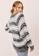 [Color: Black/White/Dove] A model wearing a cozy  slouchy, oversized fuzzy sweater. Featuring a deep v neckline and black, grey and white stripes. Perfect for fall styling. 