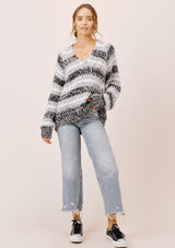 [Color: Black/White/Dove] A model wearing a cozy  slouchy, oversized fuzzy sweater. Featuring a deep v neckline and black, grey and white stripes. Perfect for fall styling. 