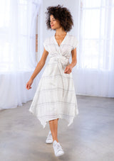 [Color: Ivory/Black] A model wearing a lightweight gauze, plaid wrap dress with tie back detail and handkerchief hem.