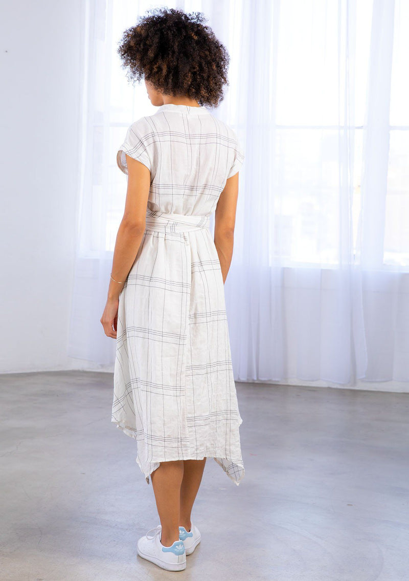 [Color: Ivory/Black] A model wearing a lightweight gauze, plaid wrap dress with tie back detail and handkerchief hem.