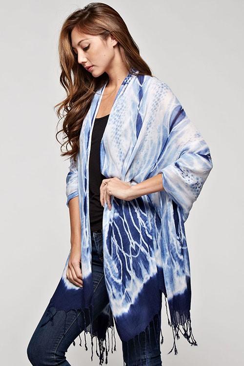 [Color: Indigo] A brunette model wearing a blue tie-dye bohemian scarf that can be styled as a sarong for the beach and draped as a scarf for a chic, cozy look.