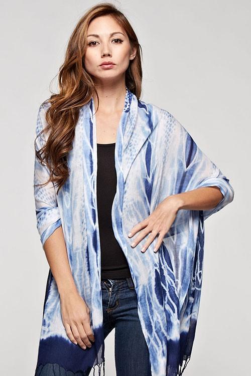 [Color: Indigo] A brunette model wearing a blue tie-dye bohemian scarf that can be styled as a sarong for the beach and draped as a scarf for a chic, cozy look.