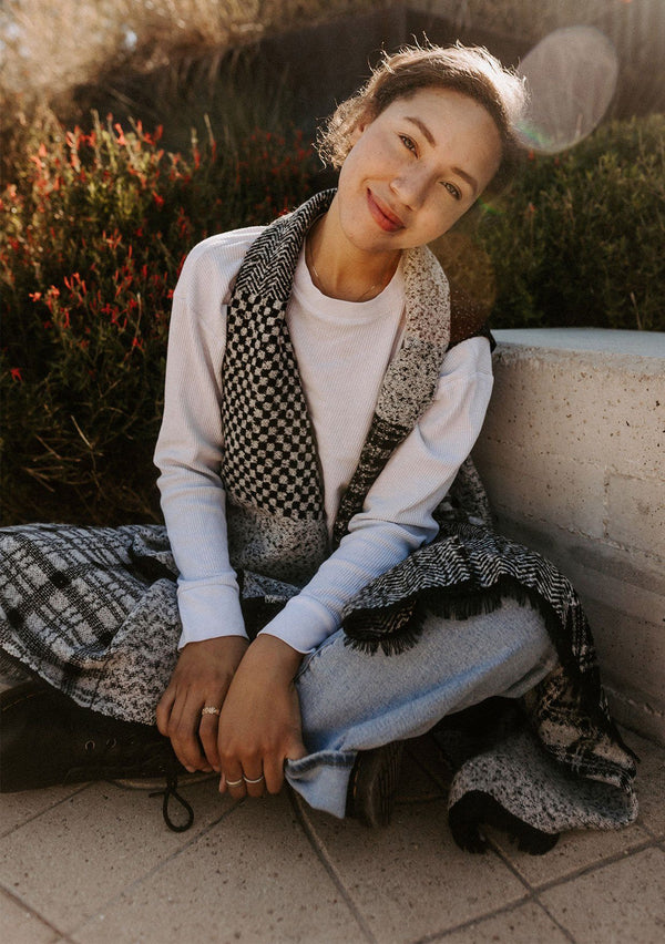 [Color: Black/OffWhite] Beautiful model wearing an effortlessly chic blanket style shawl vest with checkered and argyle patchwork details. Sweater vest shawl is black and white and extra soft.