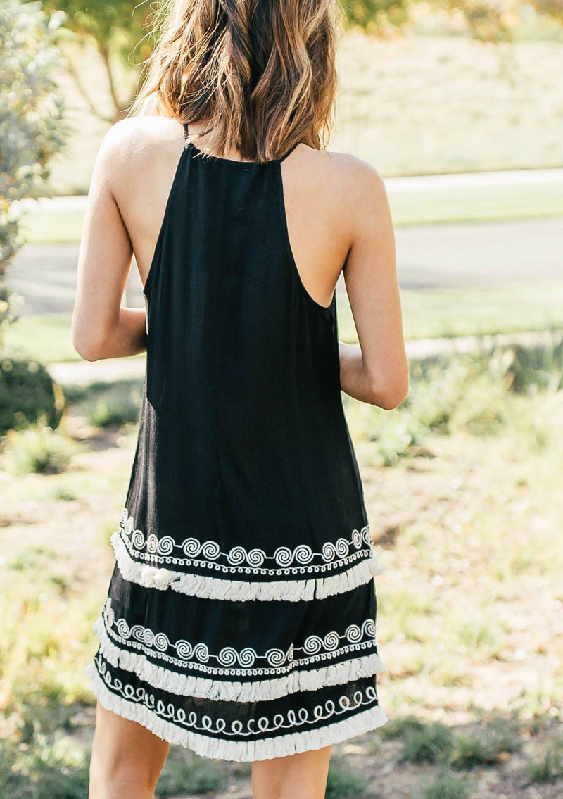 [Color: Black] A racerback mini dress with a drawstring neckline, embroidered details, and layered fringe hemline. 