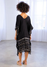 [Color: Black] A model wearing a block print caftan. With a v neckline in front and back and a tassel trim. 