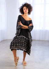 [Color: Black] A model wearing a block print caftan. With a v neckline in front and back and a tassel trim. 