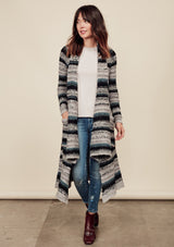 [Color: Grey/Teal/Black]  A front facing image of a brunette model wearing a bohemian striped knit duster cardigan in grey and blue with a shawl collar, side pockets, and a cozy, draped fit perfect for layering over denim.